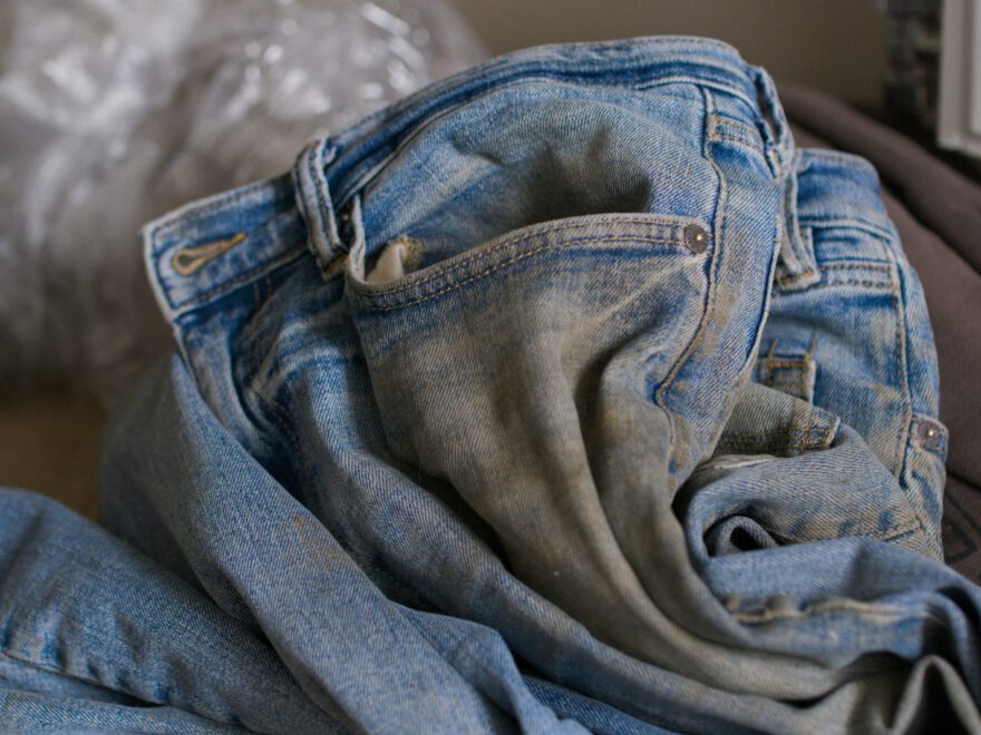 a pile of jeans sitting on top of a bed