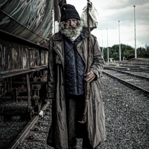 a man with a long beard standing next to a train